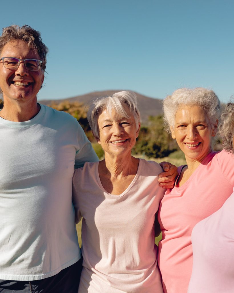 Portrait of multiracial cheerful senior friends standing against clear sky in yard at nursing home. Copy space, summer, unaltered, friendship, togetherness, support, assisted living and retirement.